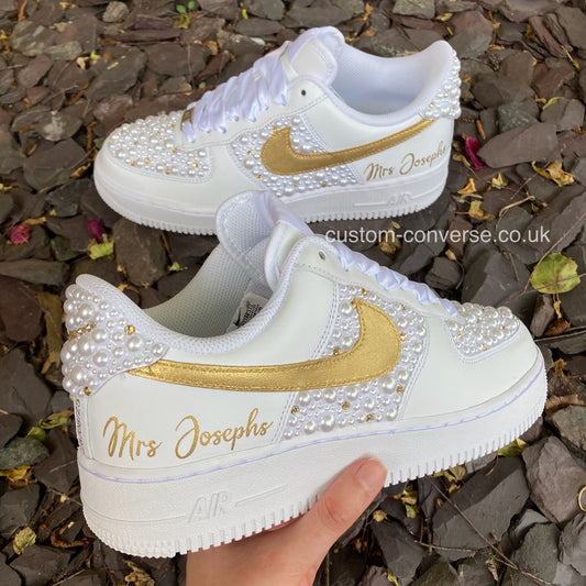 Pair of made-to-order White Pearl and Gold Linked Rings Wedding Air Force 1 trainers displayed at an angle